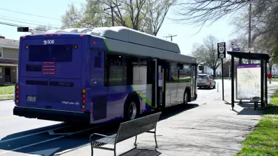 Purple GRTC bus stopped at a bus station with bench and shelter in Richmond, Virginia.