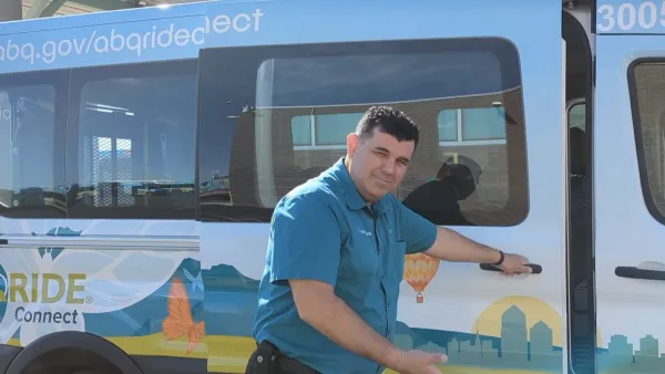 Man in teal shirt opening door to white microtransit shuttle with cactus graphics and making inviting gesture toward the camera.