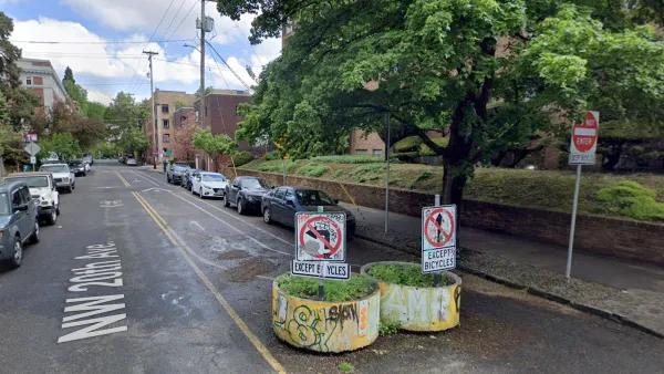 Two yellow concrete planters with graffiti on one-way street in Portland, Oregon designed to divert car traffic while allowing cyclists and pedestrians through.