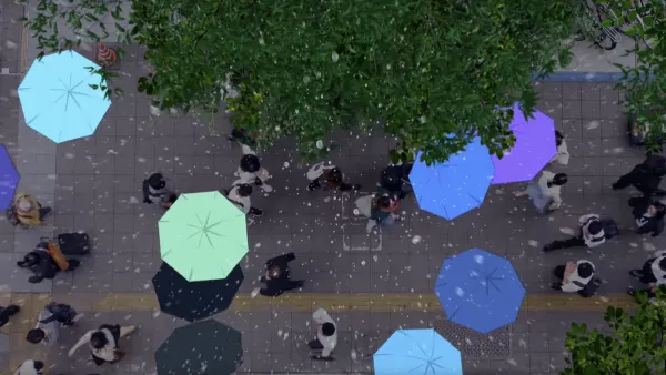 Top-down view of people walking down street with their umbrellas highlighted in bright blue-ish colors.