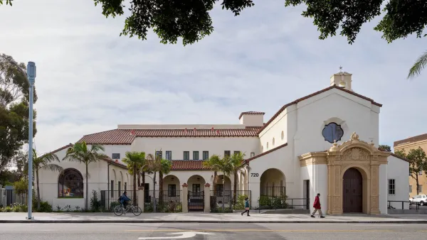 Spanish Revival building in Los Angeles, former mortuary turned apartments with two people walking and one biking by in front.