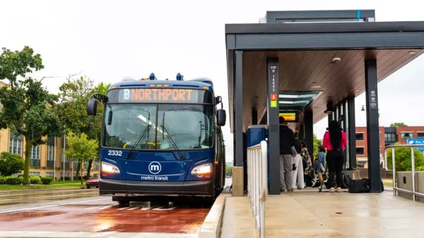 Blue transit bus stopped at outdoor station with covered platform in Madison, Wisconsin.