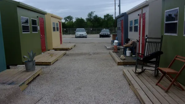 Row of green and yellow tiny homes in Esperanza Community shelter in Austin, Texas.