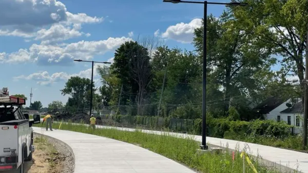 Workers building paved two-sided bike and walking trail next to single-family homes in Detroit, Michigan.