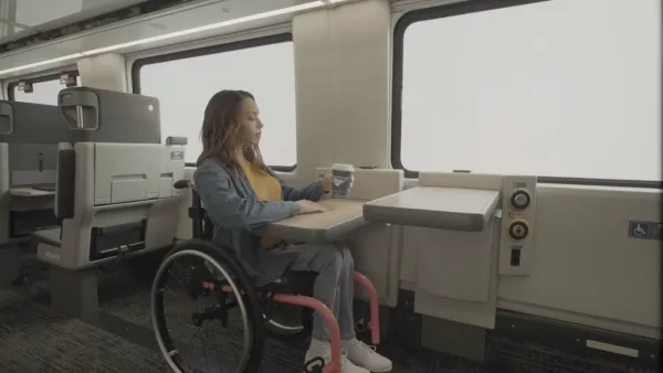 Woman in wheelchair sits at table next to window on Amtrak train.
