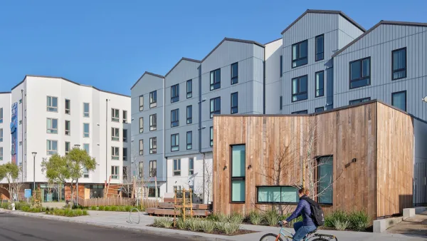 Rendering of Shirley Chisholm Village four-story housing development with person biking in front.