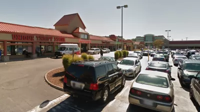 A typical American shopping center, with a thrift store at one end and a parking lot full of cars.