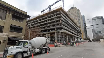 Construction on a high-rise, with cement trucks and tall cranes, is visible on an Austin Street.