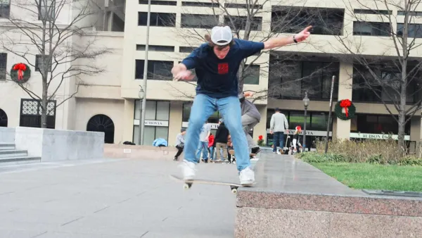 Boy wearing jeans and white cap skateboards off marble ledge in Freedom Park, Washington DC.