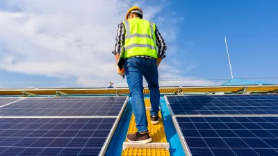 Worker standing between solar panels on roof