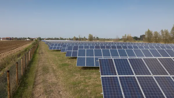 Solar panels are lined up on agricultural land. 
