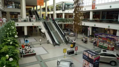 View form second story inside Southdale Mall in Edina, Minnesota with escalators and model cars parked on downstairs floor.