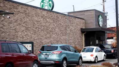 A line of cars wait at the drive-thru window of a starbucks.