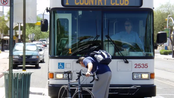 Man loading or unloading bike from rack on front of public transit bus in Tucson, Arizona.