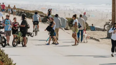 Crowds of people walking and biking along waterfront in Sunset Dunes Park in San Francisco, California on a sunny day.
