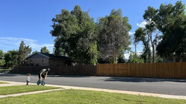 Parent teaching small child to ride bicycle on a suburban street.