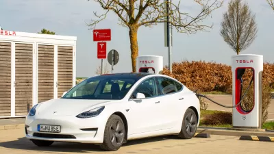 A Tesla Model 3 with a European license plate is connected to a Tesla Supercharger.