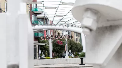 A picture of a decorative sign announcing “The Domain” surrounded by high density shops and apartments.
