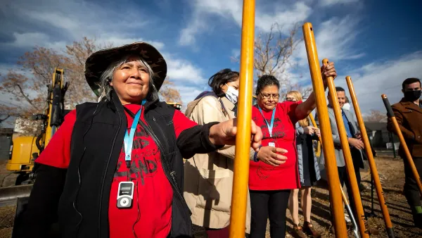 People in red shirts holding shovels for photo op at groundbreaking for community land trust project in Denver.