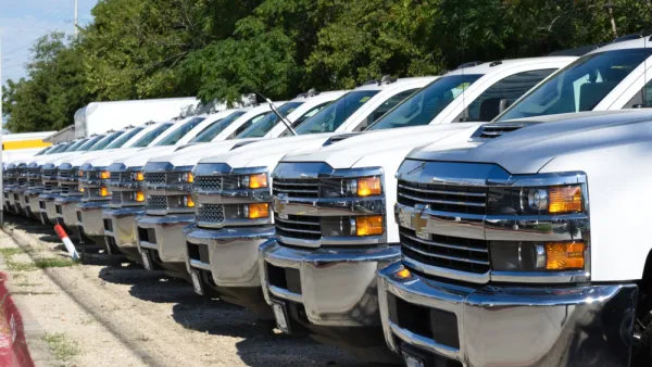 A row of white pickup trucks at a car dealership.
