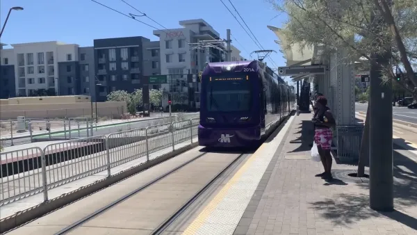 Purple Phoenix light rail train pulling into outdoor station.
