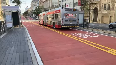 Red bus only lanes on Van Ness Avenue in San Francisco, California with bus stopped at station.