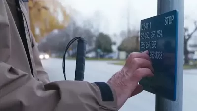 Close-up of hand reading Braille sign at bus stop in Vancouver, British Columbia.