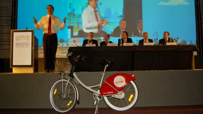 Gil Penalosa speaking on a stage at Velo-city conference in Seville, Spain, with bicycle in foreground