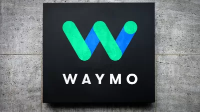 Blue and green Waymo logo on black square mounted on grey concrete background