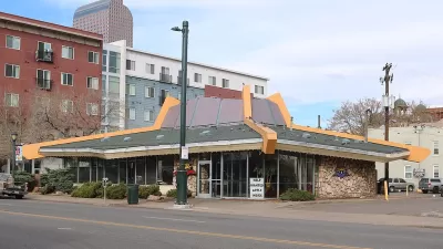 The sloped roof of a googie style building is prominently featured in this image of a restaurant in Denver. Tall apartment buildings are seen in the background.