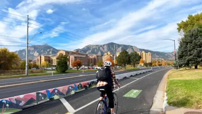 Bike lane in Boulder, Colorado with tall concrete barrier separating it from vehicle lanes and one cyclist passing by.