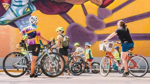 Group of cyclists wearing helmets pause in front of a mural in El Paso, Texas.