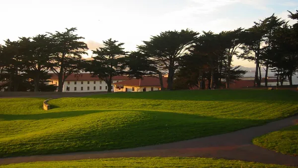 Green lawn with fort mason buildings in background beyond trees
