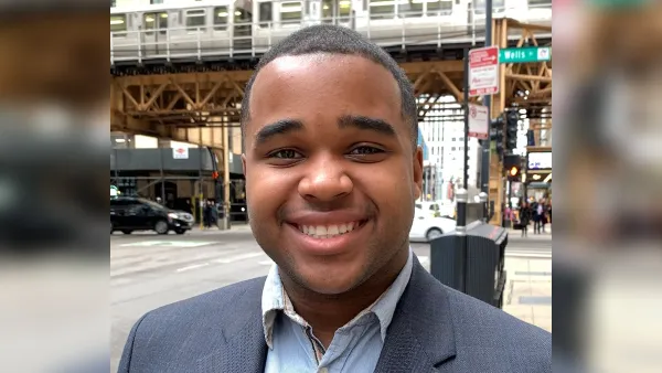 Head shot of smiling young man standing on busy urban street.