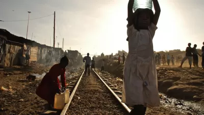 Two young girls carry water on the train tracks that run through the Kibera Slum
