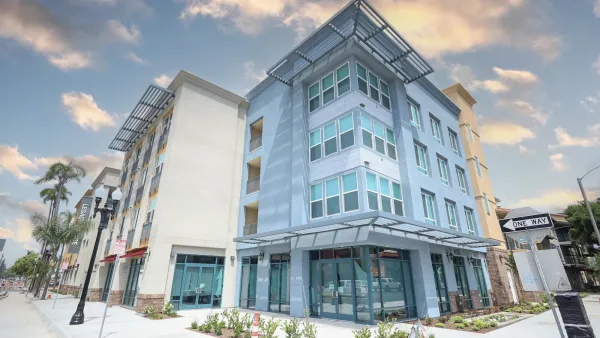 Modern four-story glass-fronted apartment building.