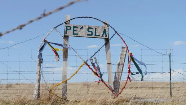 A sign reading Pe’ Sla in a grassy prairie.