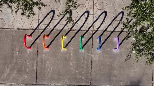 6 bike racks, shot from above, each painted a color of the Pride rainbow