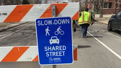 Close-up of blue "Slow Down - Shared Street" sign on orange and white barricade in Denver, Colorado.