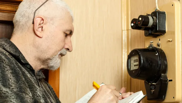 Man looking at electric meter and writing something down.