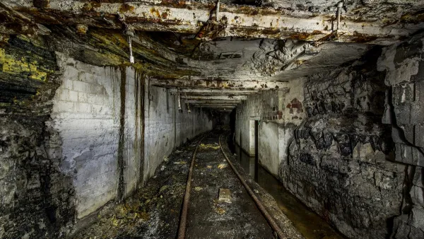 An abandoned mine in Pennsylvania. The ceiling is low, the walls and floors are gray, and mine cart tracks run along the bottom.