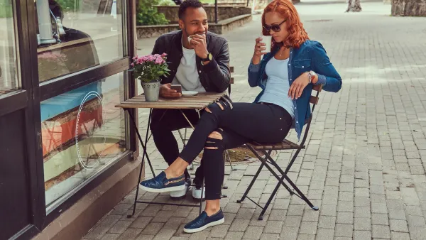 Young couple sitting at a small sidewalk cafe table.