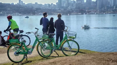 Three people standing next to Lime bikeshare bikes looking out over water toward the Seattle skyline