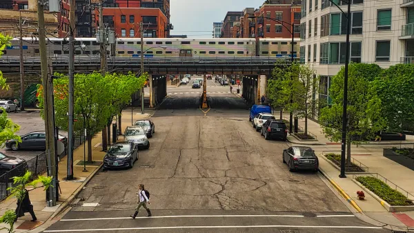Chicago elevated train passing over street with parked cars.