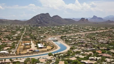 Aerial view of irrigation canal winding through Scottsdale, Arizona suburb with mountains in background