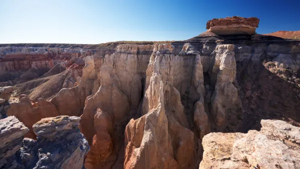 A picture of Coalmine Canyon, a rust-colored canyon under a blue sky.
