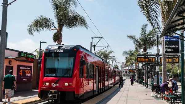 A red San Diego trolley car stopped at a platform with people waiting in San Ysidro, California near the Mexico border.