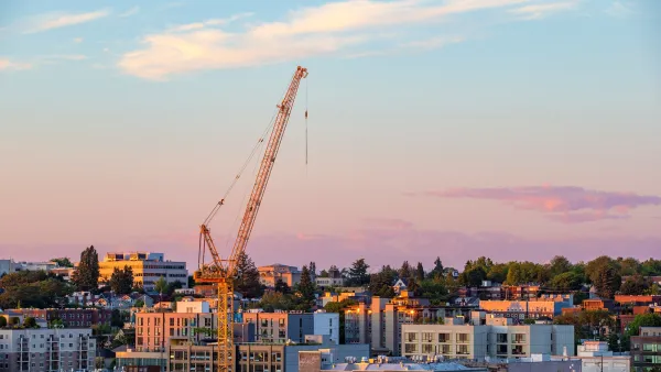 Seattle skyline in low-rise area with yellow construction crane rising over buildings at dusk.