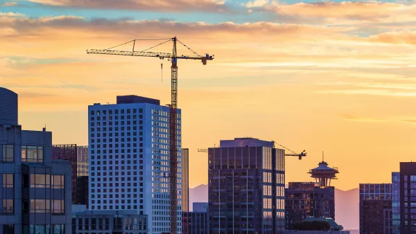 Construction crane against downtown Seattle skyline at sunset.