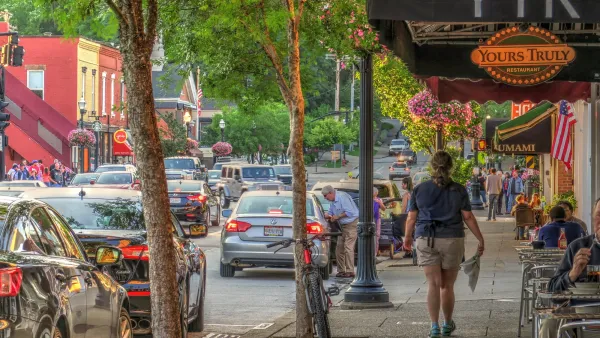 Person walking down wide sidewalk next to restaurant patio tables in Chagrin Falls, Ohio.